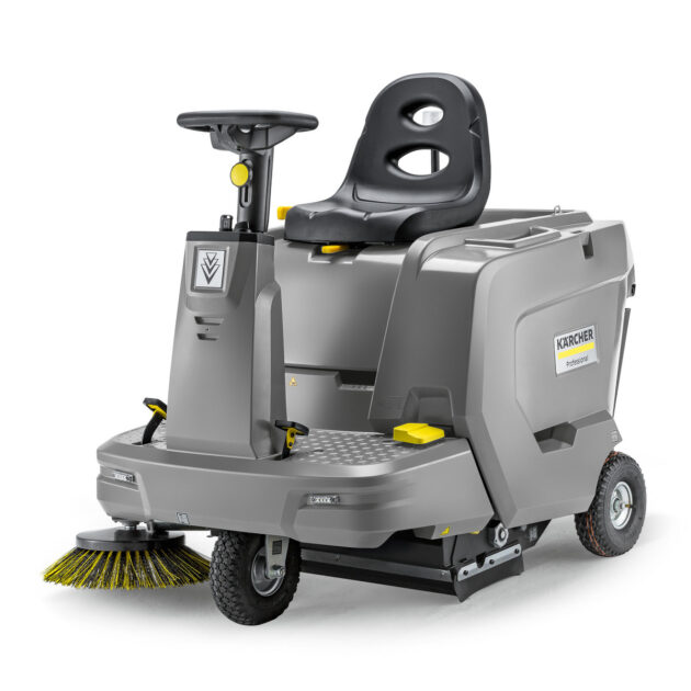 An image of a gray and yellow Vacuum Sweeper KM 85/50 R BP Pack with an attached side brush, featuring a comfortable seat and a steering wheel, isolated on a white background.