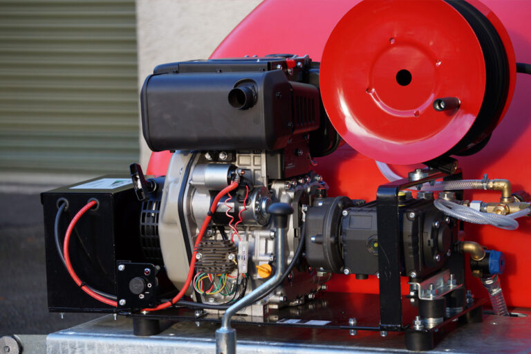 Close-up of a red and black industrial machine featuring a motor, pipes, and cabling, set against a gray metallic background.