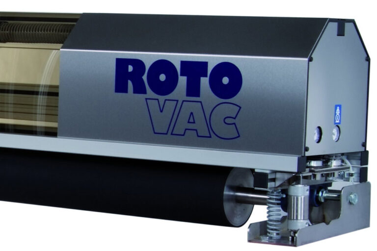 Close-up of a silver and blue industrial cleaning machine labeled "roto vac", showing intricate mechanical details including brushes and metal components.